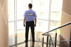 Addetto alla vigilanza che guarda fuori una vetrata di un edificio