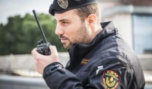 Addetto alla vigilanza armata che usa il walkie talkie Addetto alla vigilanza armata che usa il walkie talkie