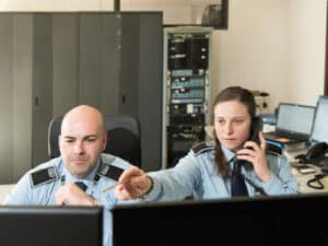 Due addetti alla sorveglianza che comunicano con un loro collega mentre controllano i loro monitor